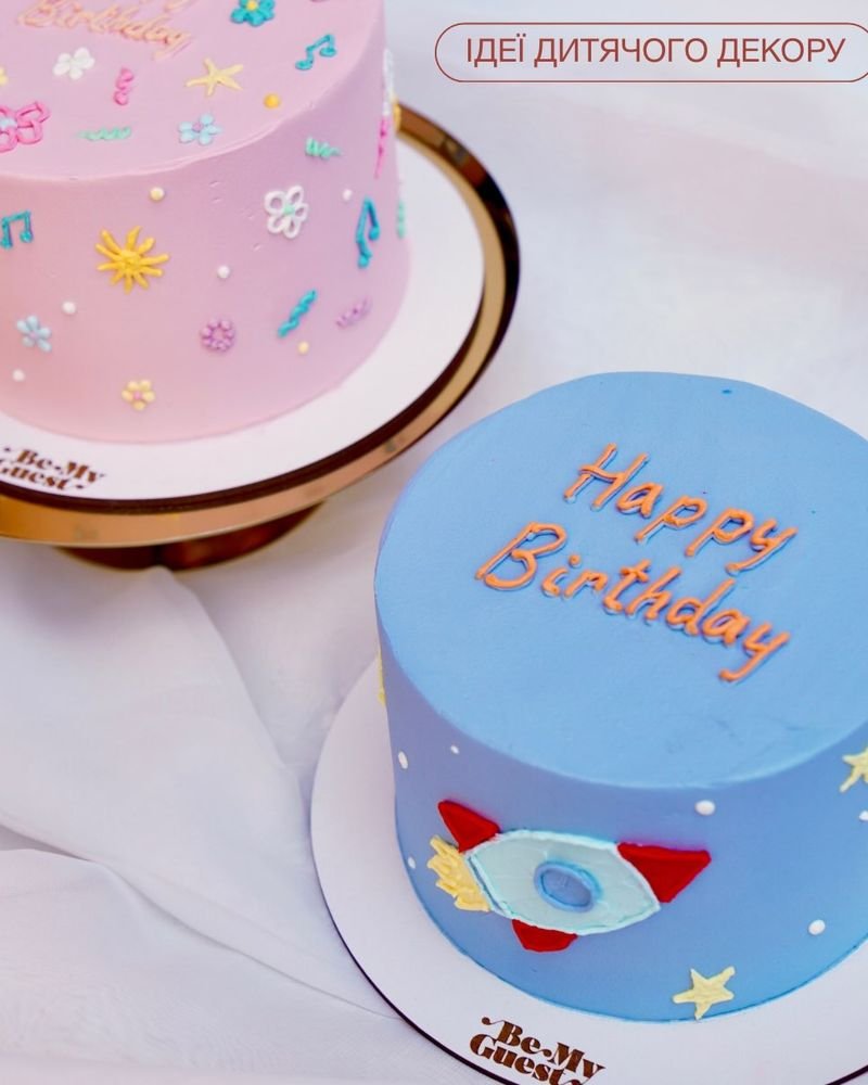 Блакитний торт з ракетою та написом Happy Birthday і рожевий торт із малюнками